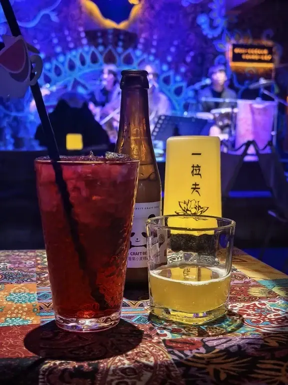 Two drinks on a table facing the live-music stage at Yilafu in Lijiang