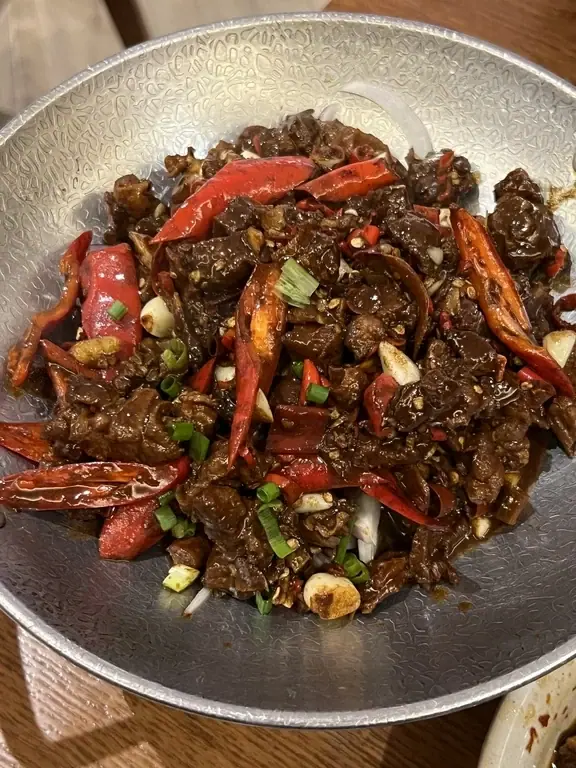 Stir-fried meat with red peppers in a white bowl at Pang Mao Tuo in Shanghai