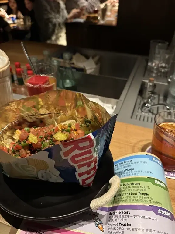 Bar food, a bottle and a can on the counter at Pony Up Shanghai